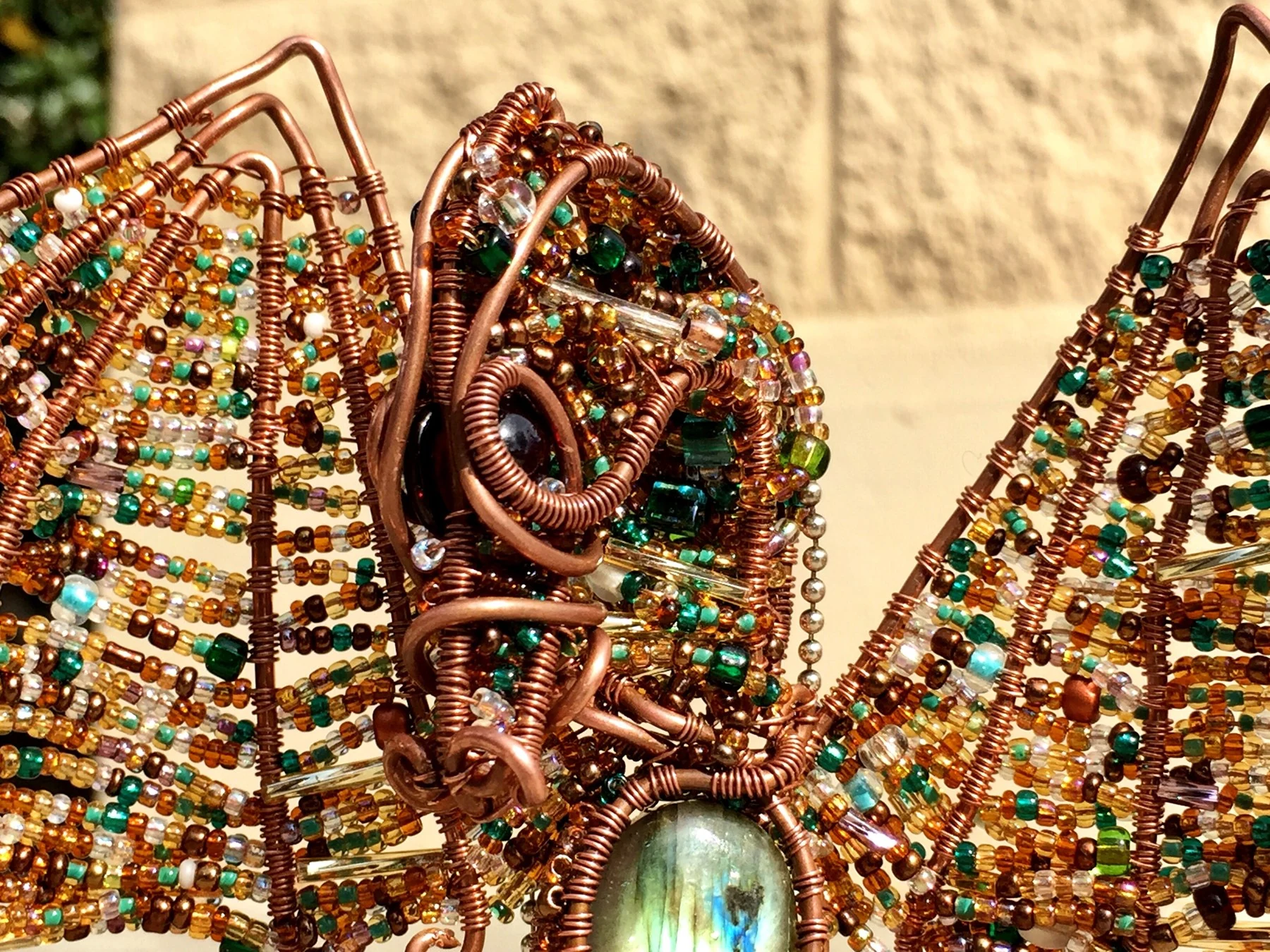 Close view of the dragon's copper framework and densely beaded wing.